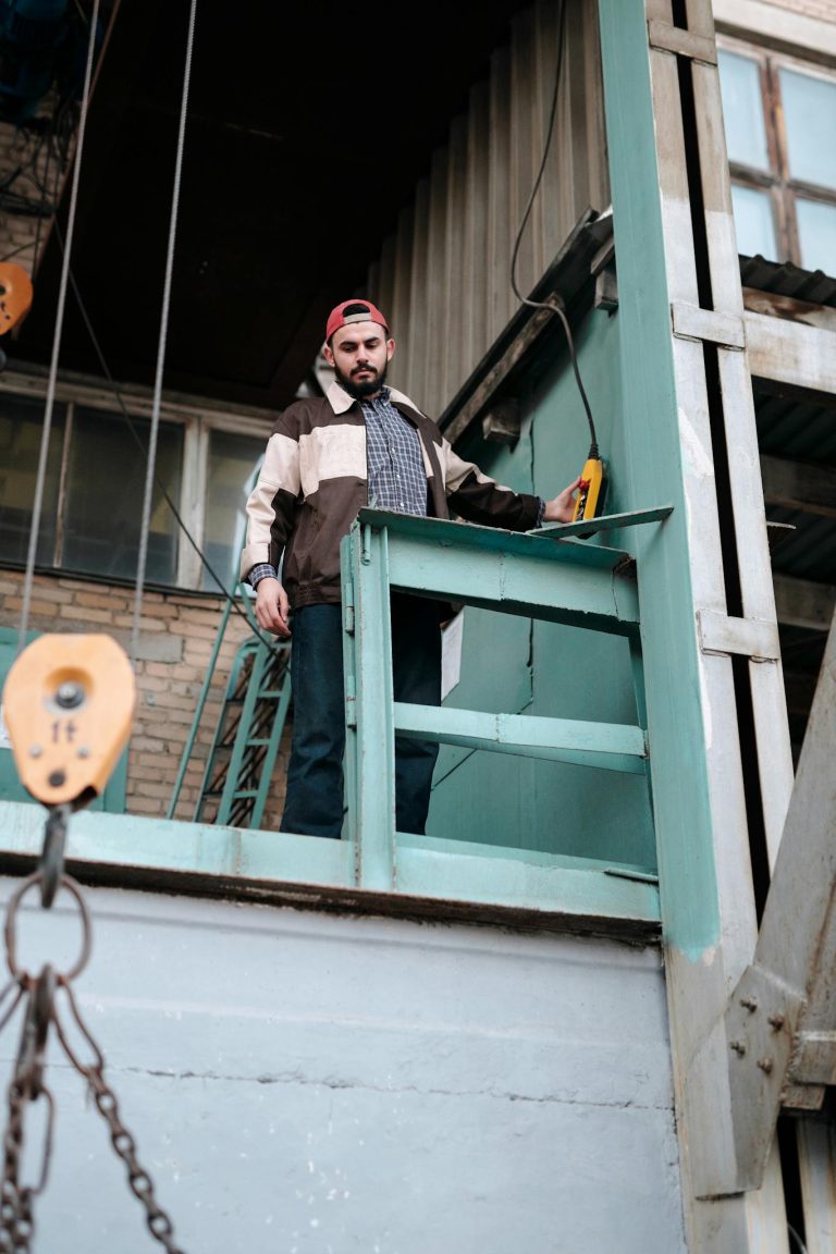 Industrial worker using crane control panel in a warehouse setting.