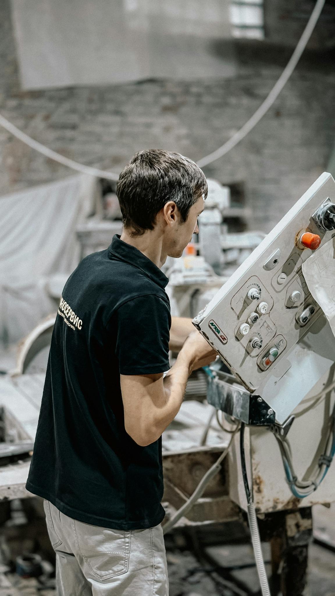 Young worker operating a machine in an industrial workshop, focused on tasks.